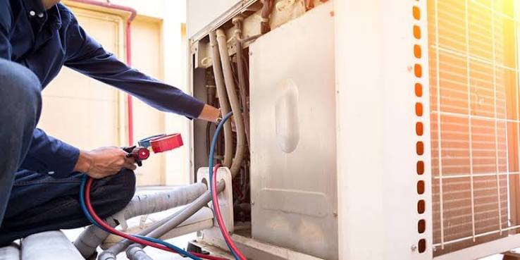 Technician using gauges to diagnose an open HVAC cabinet