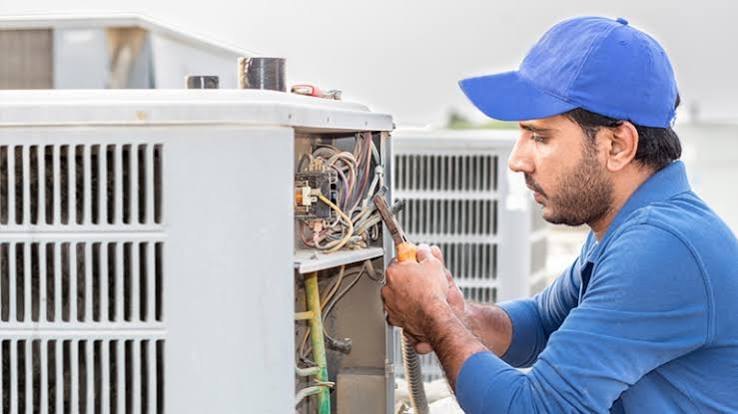 HVAC technician inspecting the electrical panel of an outdoor air conditioning condenser