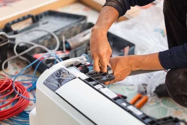 Technician working on indoor HVAC unit wiring and indoor-air components