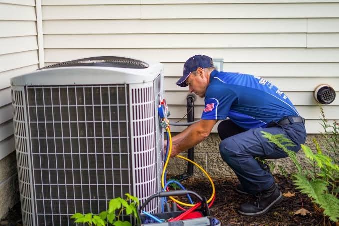 Technician checking a residential outdoor condenser during maintenance